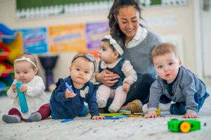 A teacher sitting with a group of young children on a rug