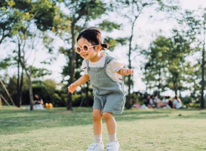 A young girl in sunglasses playing in a park